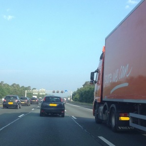 Tekst op een rode vrachtwagen op de snelweg: Sure we can. Dat wekt vertrouwen.
